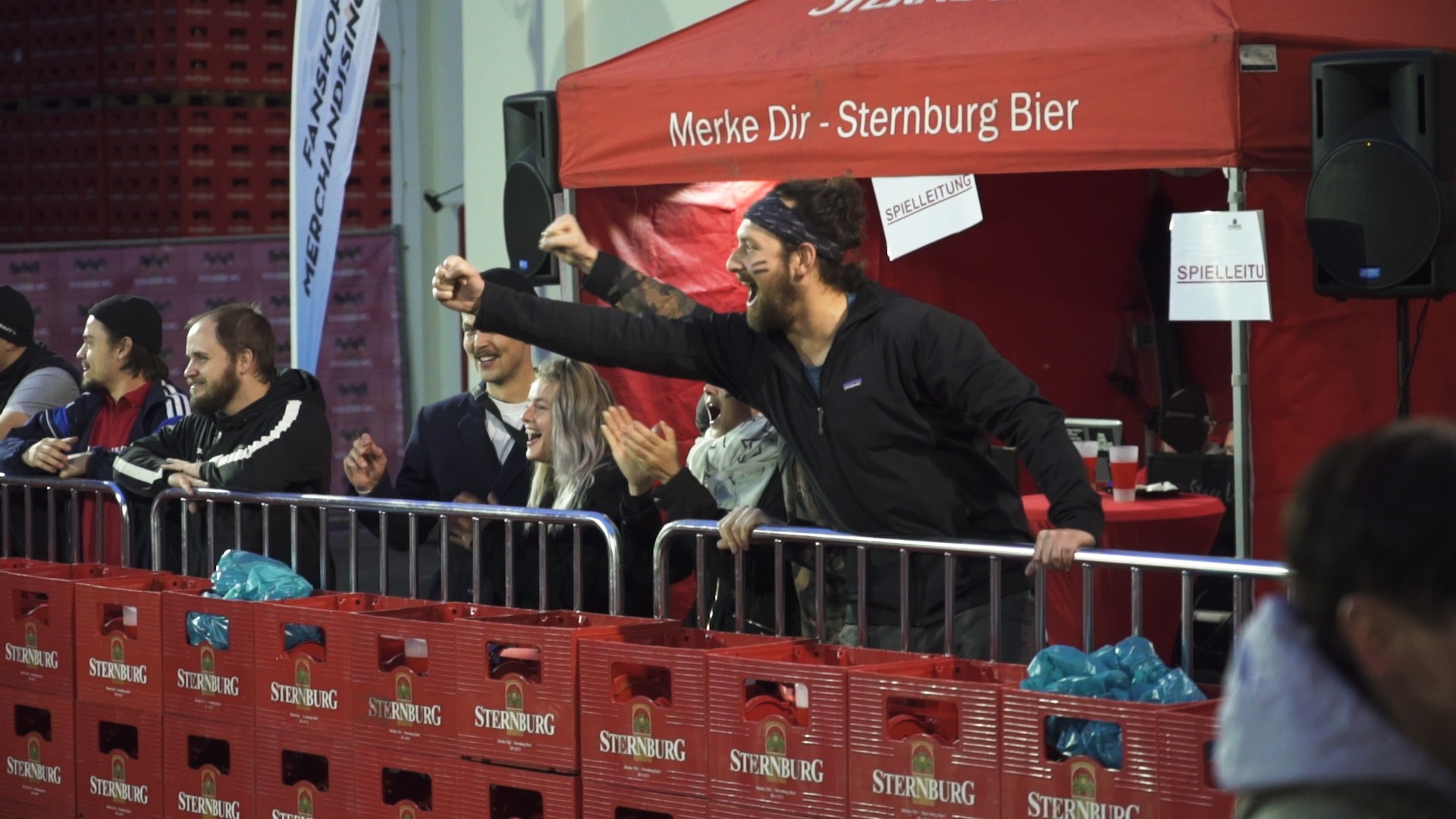 Eine Gruppe begeisterter Menschen jubelt und feiert an einem Veranstaltungsort.