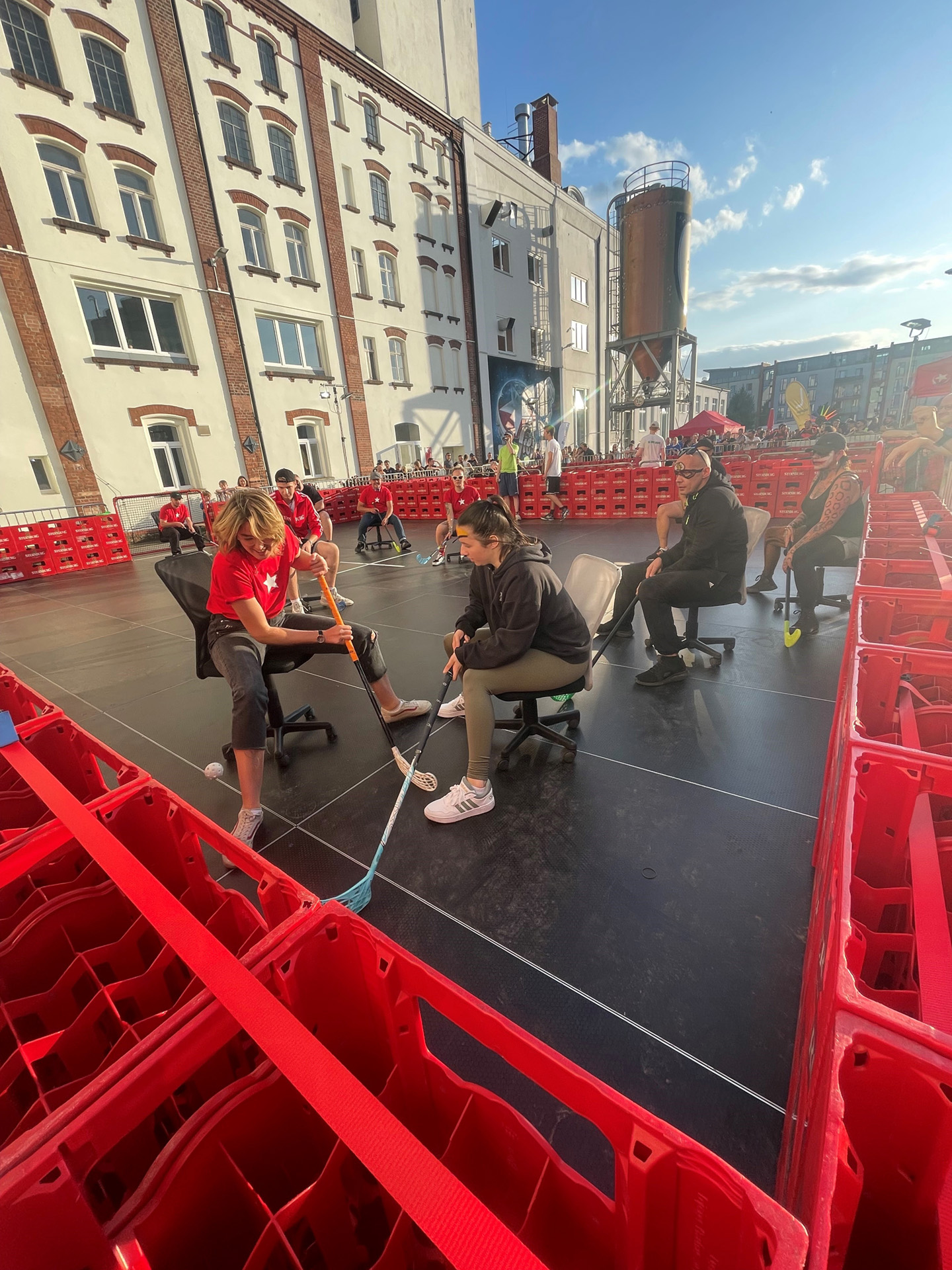 Mehrere Menschen nehmen an einem Tauziehen teil, umrahmt von roten Plastikbarrieren.
